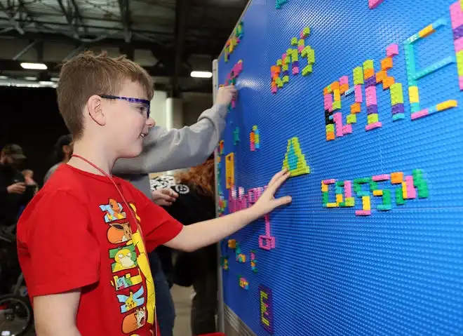 Landon Melvold, 8, of Peosta adds to the graffiti wall at Brick Fest Live featuring life-sized models made from Legos, hands-on activities, and a meet-and-greet with Manny from the 