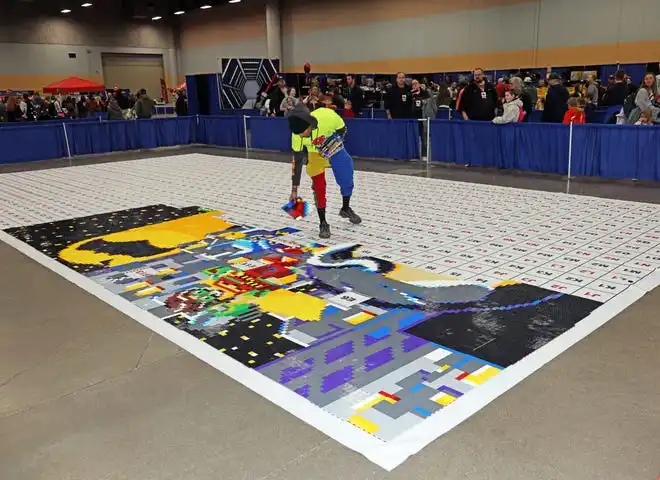 A giant floor mural is carefully assembled at Brick Fest Live featuring life-sized models made from Legos, hands-on activities, and a meet-and-greet with Manny from the 