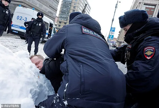 Police officers detain a man during a gathering in memory of Russian opposition leader Alexei Navalny near the Wall of Grief monument