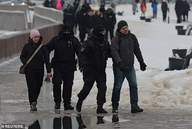 Law enforcement officers lead people away from the monument to the victims of political repressions