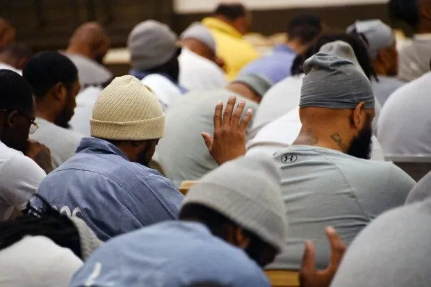 Inmates at the Roxbury Correctional Institution bow their heads as Darryl Strawberry, a former Major League Baseball right-fielder who is an ordained minister, leads them in prayer. Strawberry spoke with them about some of the challenges in his life and turning to God. (Kim Hairston/Staff)