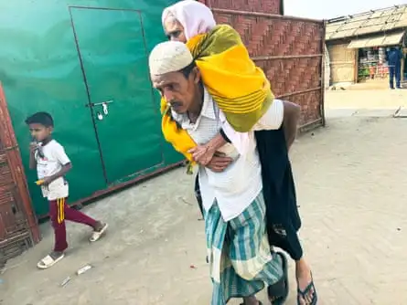 A man carries his mother to a healthcare facility in the Rohingya refugee camp in Cox’s Bazar, Bangladesh