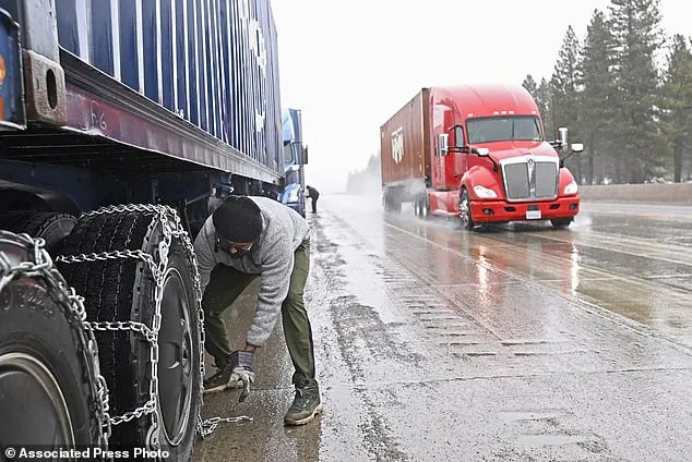 Mangal Singh parks his truck off the I-80 to put chains on his truck wheels in preparation for the snow storm over the Sierra Nevada on Thursday, Feb. 29, 2024, in Truckee, Calif. A Pacific storm packing powerful winds and heavy snow is shaping up to be the strongest of the season, forecasters say. (AP Photo/Andy Barron)