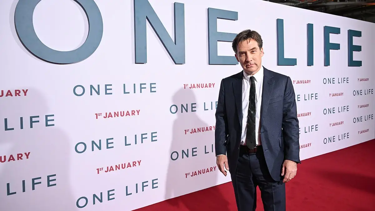 James Hawes in front of One Life signage on red carpet