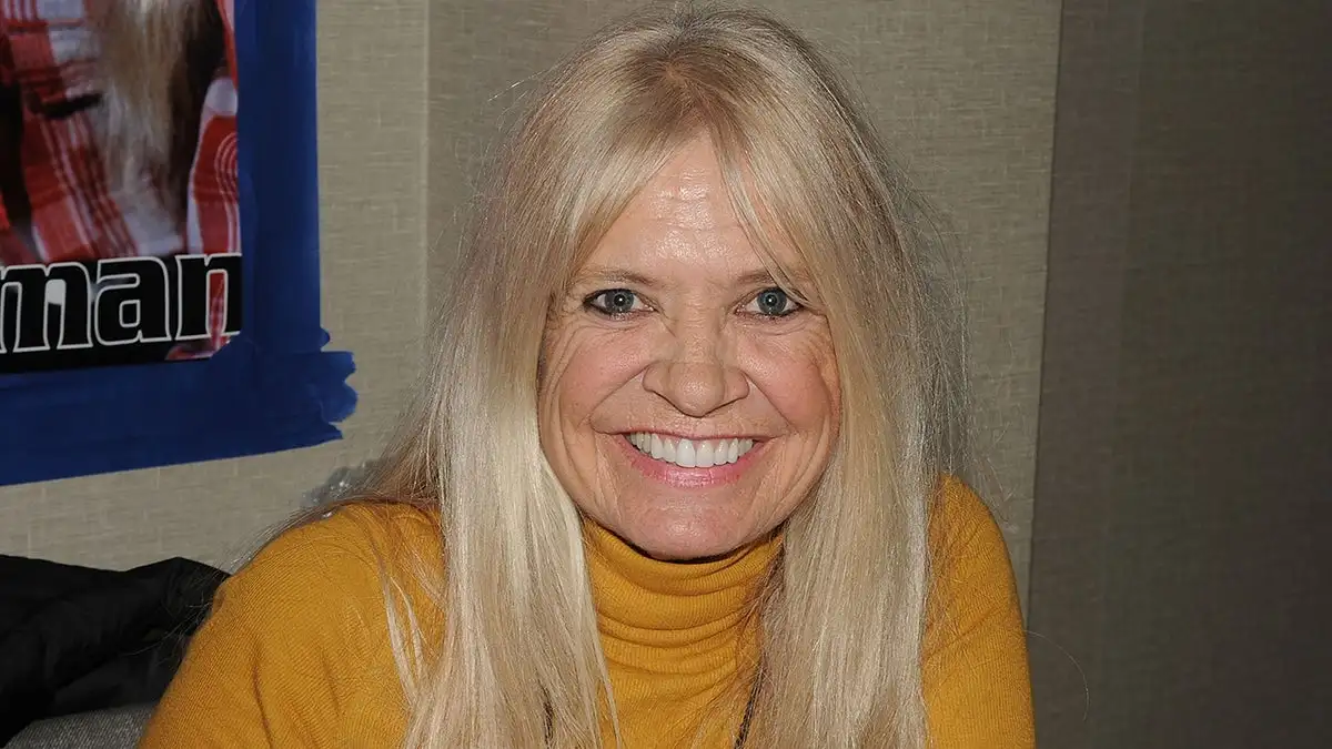 Kathy Coleman smiling wearing a yellow turtle neck