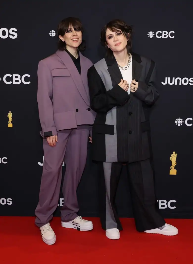 Tegan and Sara on the Juno Awards red carpet wearing oversized, asymmetrical suits and white sneakers.