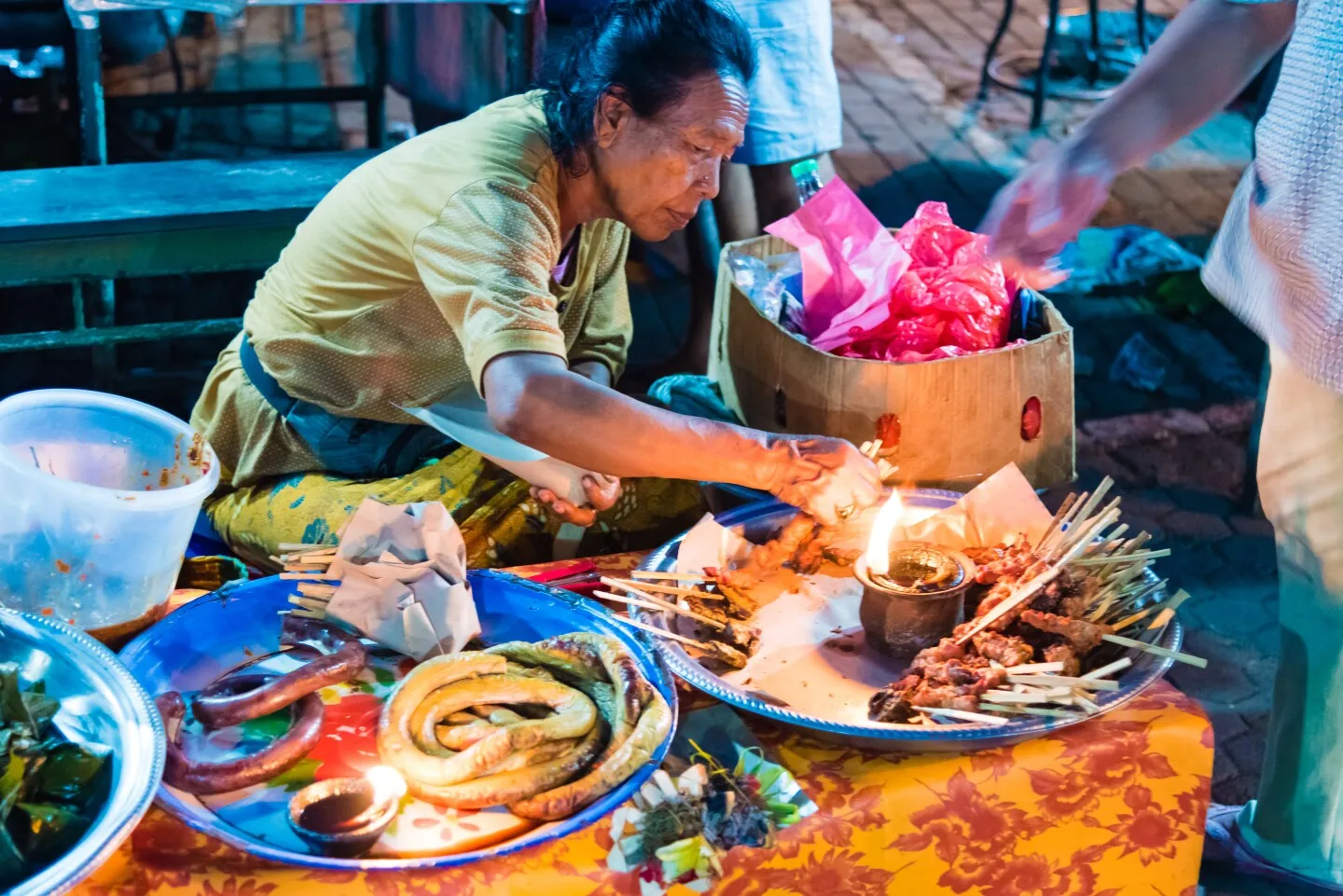 Person standing over large plates of street food