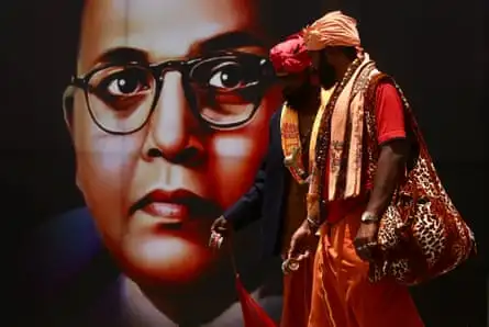 Two Indian men pass a poster of a spectacled Indian man