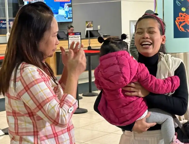 A woman cries on the left. Another woman on the right laughs and cries while holding a child.