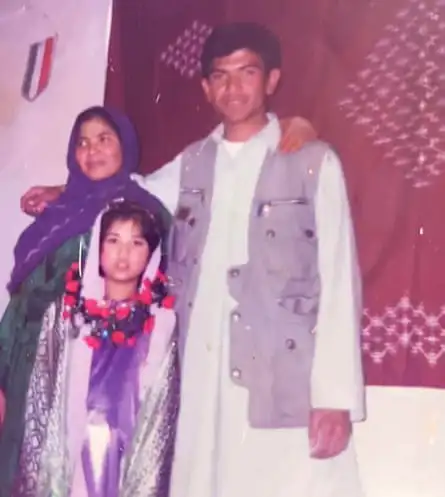 A little girl poses for a photo between a woman in a headscarf and a young man