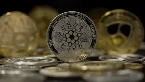 The Cardano token with other gold and silver tokens in the background.