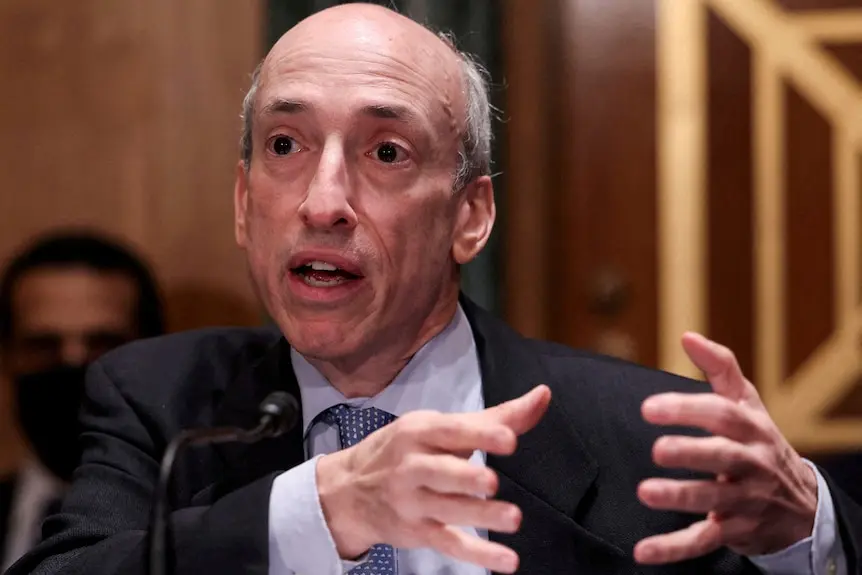 An older man in a suit with some grey hair on the sides of his head waves his hands