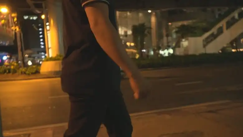 An anonymous man walks through a city at night.