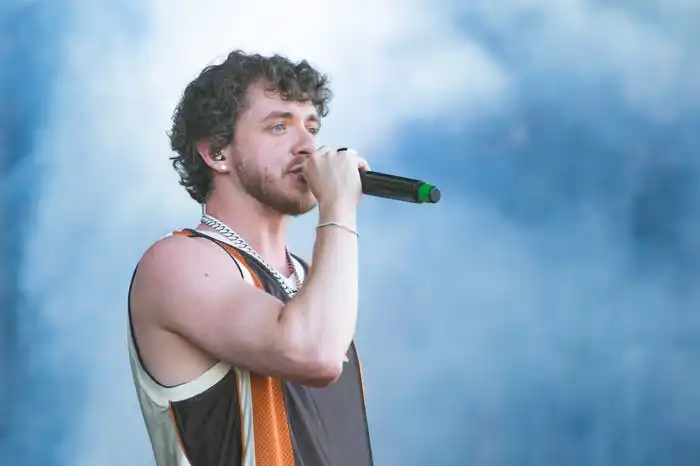 Jack Harlow performs in a brown and orange jersey and silver chain on the main stage during Wireless Festival.