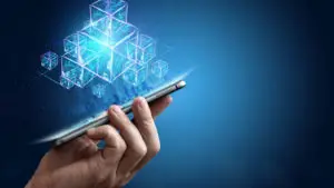 An image of a hand holding a cell phone with several visualizations of digital building blocks floating above it. representing sto platforms