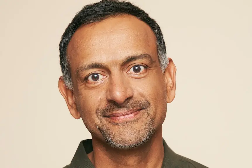 A man smiling and wearing a green collared shirt.