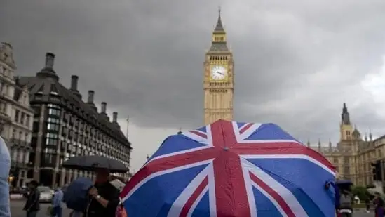 A pedestrian shelters from the rain beneath a Union flag themed umbrella.(AFP)