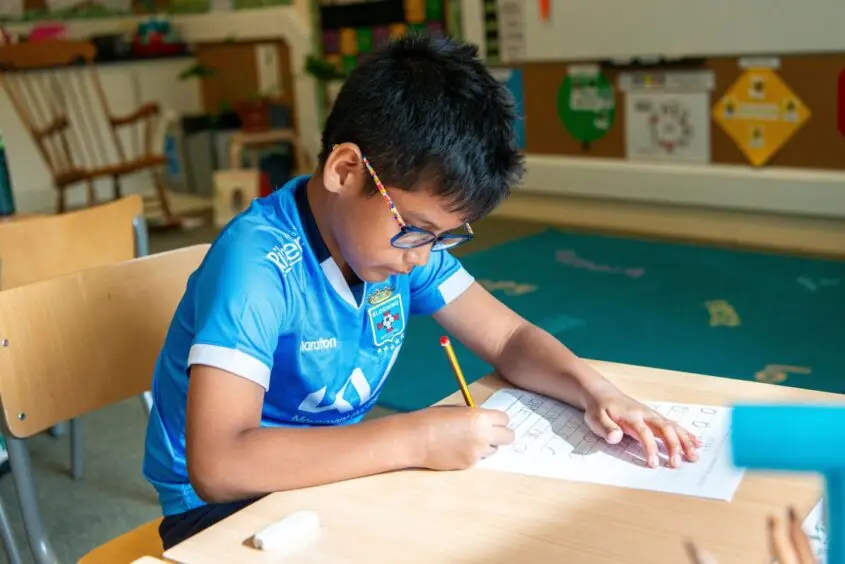 Student at International School Aberdeen working at desk.