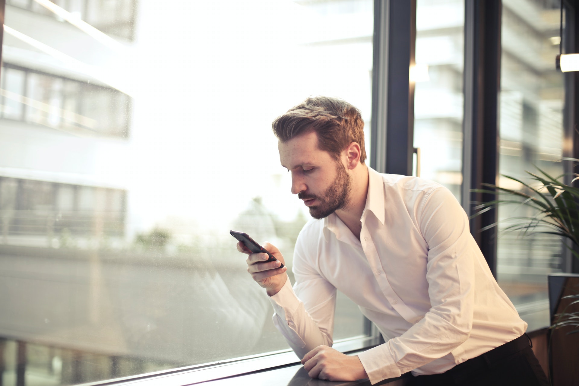 man texting near window