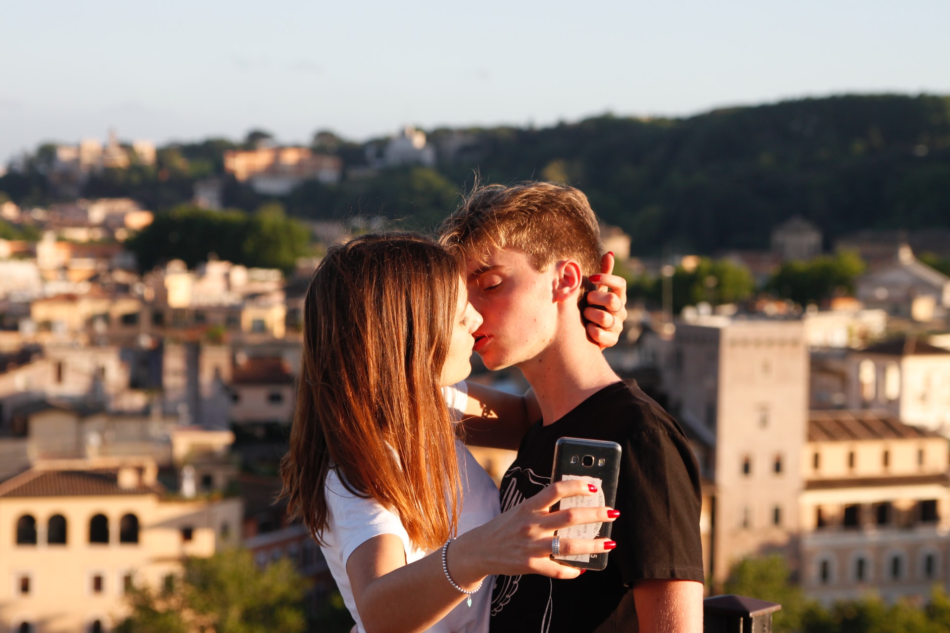 woman try to kiss man while holding smartphone