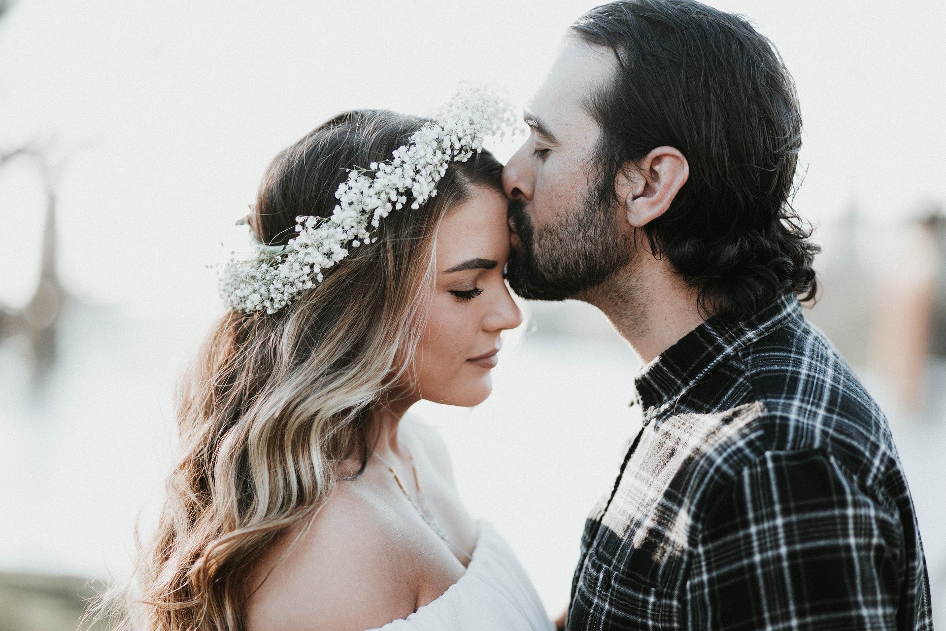 man kissing on the forehead of woman