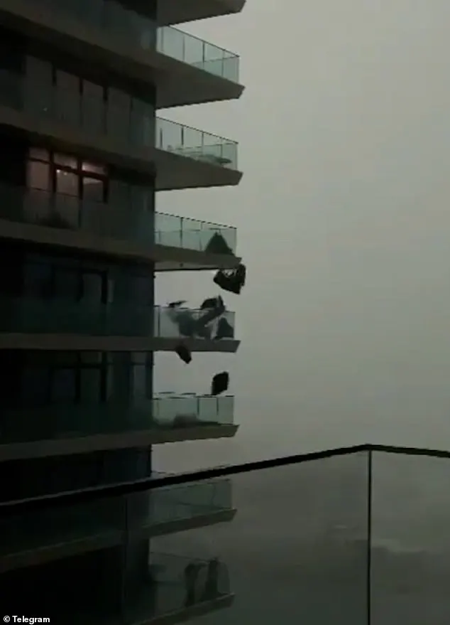 Patio furniture appears to fall from a highrise balcony amid storm conditions in Dubai