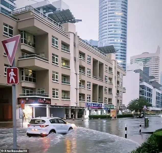 A driver is seen navigating their car through deep flood waters in Dubai