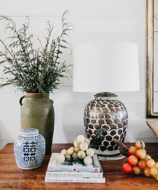 A console table with a lamp, vase and a stack of books