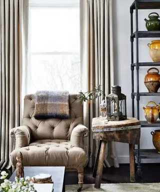 An armchair and side table next to a tall shelving unit full of colorful ceramic vases