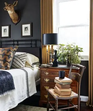 A bedroom with a tall stack of books on a chair