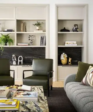 A living room with white built-in bookshelves full of plants and books