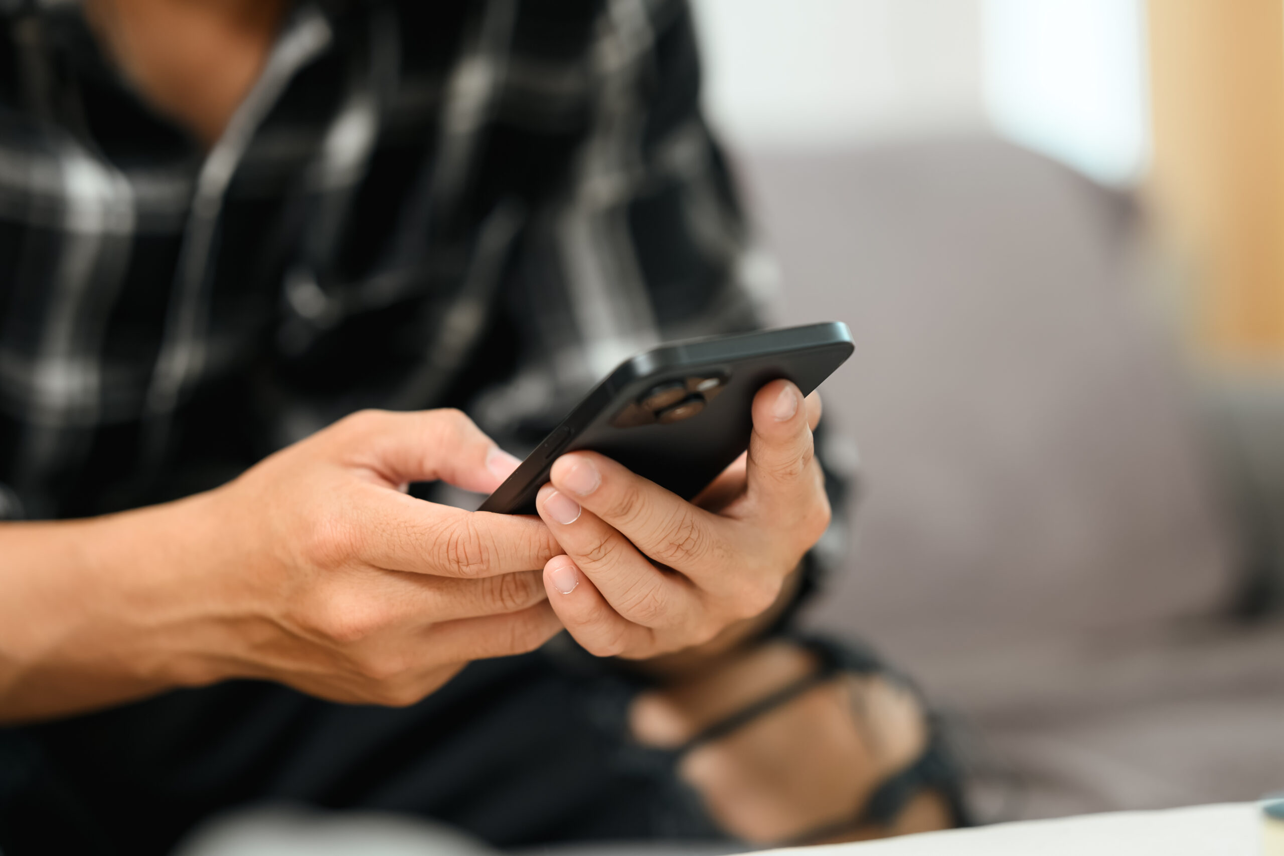 Close Up shot of man using mobile phone check in news feeds in social media.