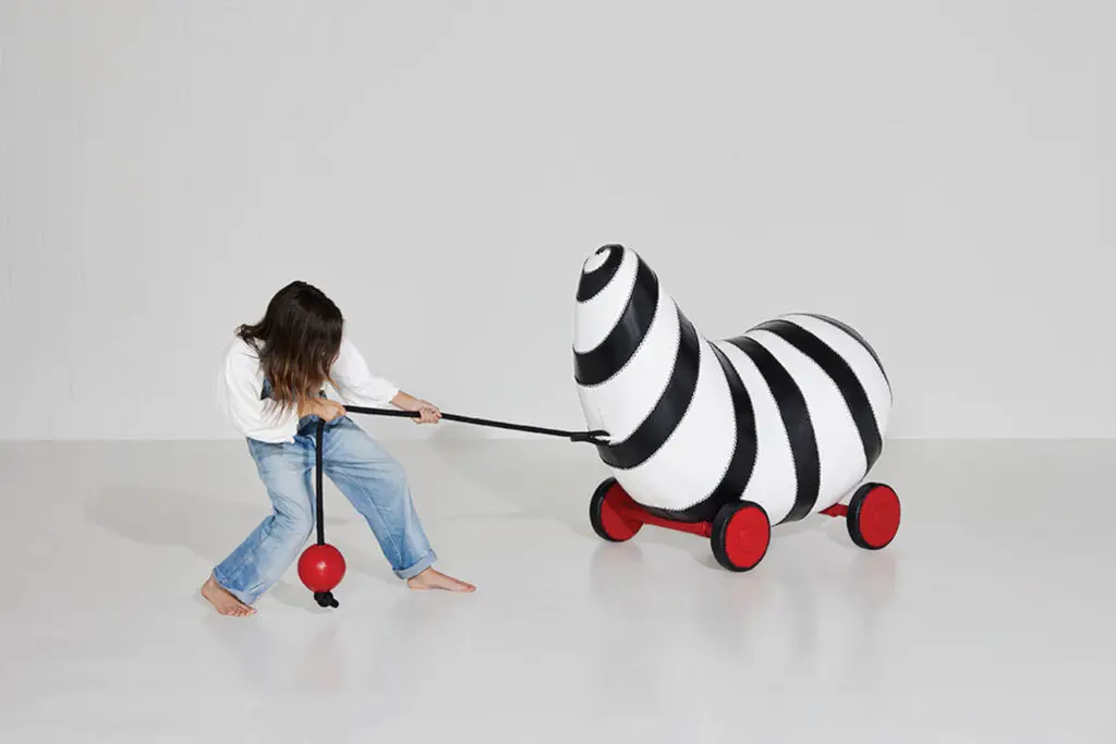woman pulling at a striped worm-like sculpture