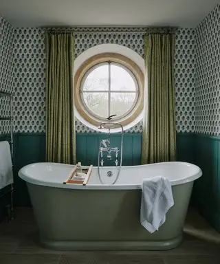 drapes vs blinds, green bathroom with round window, green drapes, green wallpaper, teal shiplap/wainscotting, green painted roll top bath