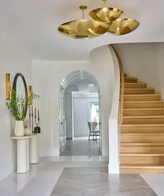 curved wooden staircase and hall with white walls and brass lamp