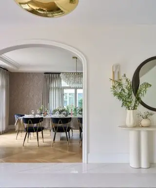 hallway with cream walls and arched opening and view to dining room