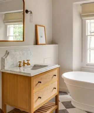 traditional bathroom with wooden vanity and beige walls and freestanding white bath