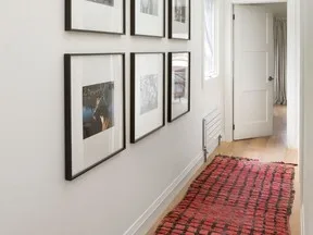 The clean, sunlight-filled hallway is the perfect setting for a family art gallery.