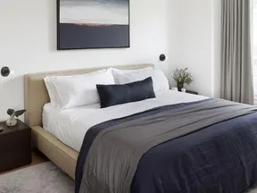 The colours in a moody painting of a tropical island at sunset are echoed in the choice of bedding.