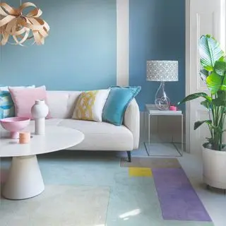 A pastel living room painted in sky blue with a colour-blocked rug