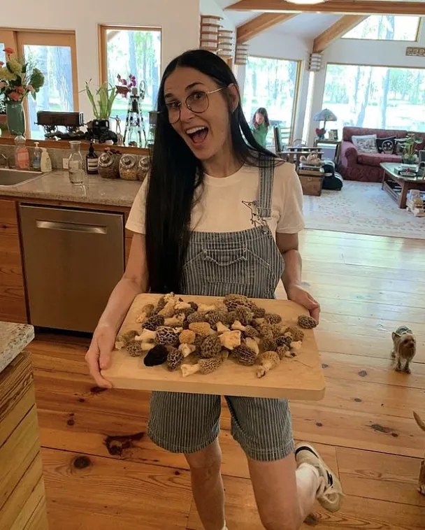 Demi moore holding board of mushrooms in kitchen