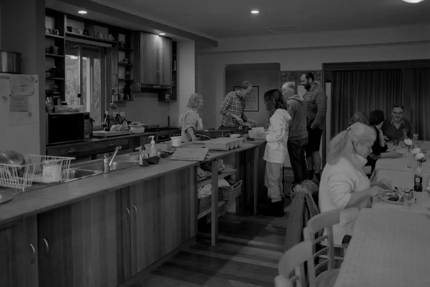 A group of people huddle around the kitchen