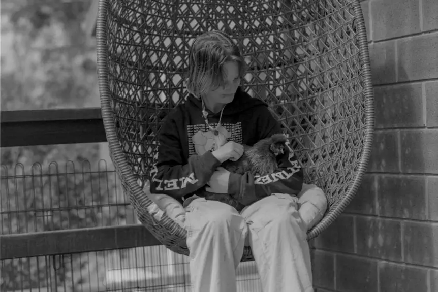 Girl holds cat while sitting on egg chair