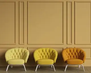 mustard yellow wall with three yellow and orange chairs in front