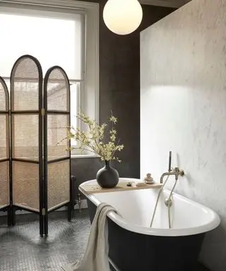 Bathroom with a textured black wall and a matte black roll top bath tub