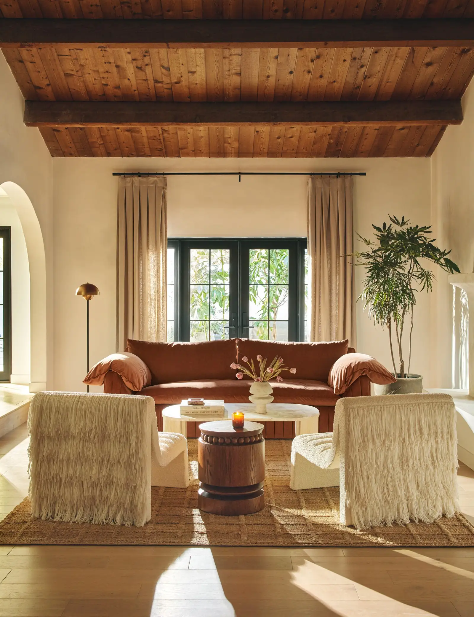 Living room with furniture designed by Carly Cushnie including a couch two accent chairs with fringe backs and an oval...