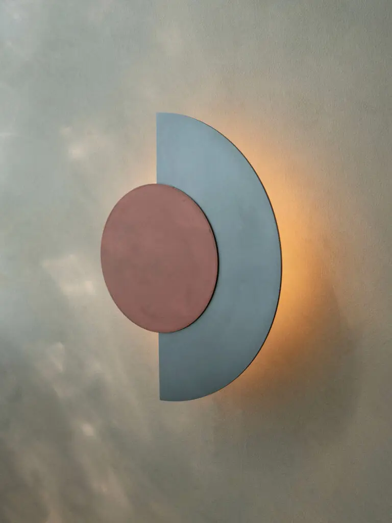 a geometric wall sconce with teal and rust colored shapes