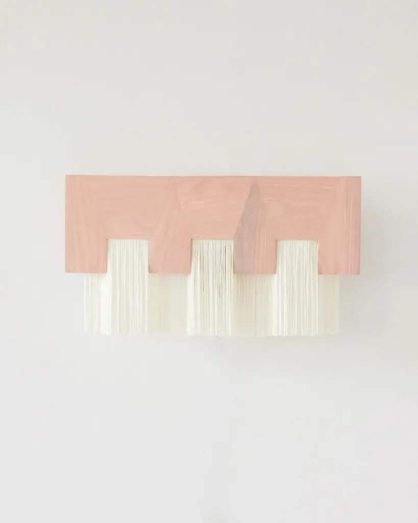 a pink rectangular wall sconce with three white lights