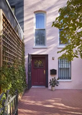 a pink house with climbing plants beside