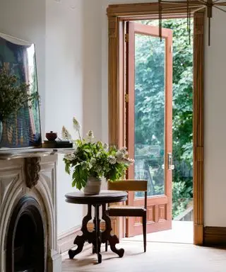 A white room with a carved fireplace, large wooden doorframe and small seating area